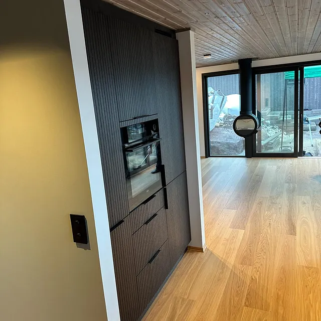 Moderne interiør med peis og gjennomgående stue og kjøkkenløsning